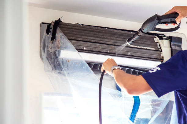 HVAC technician cleaning an indoor air conditioning unit